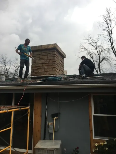 masonry contractors on the roof performing chimney tuckpointing